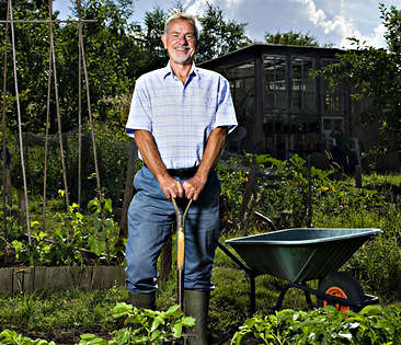 Gartenhausversicherung - Mann steht lächelnd im Garten